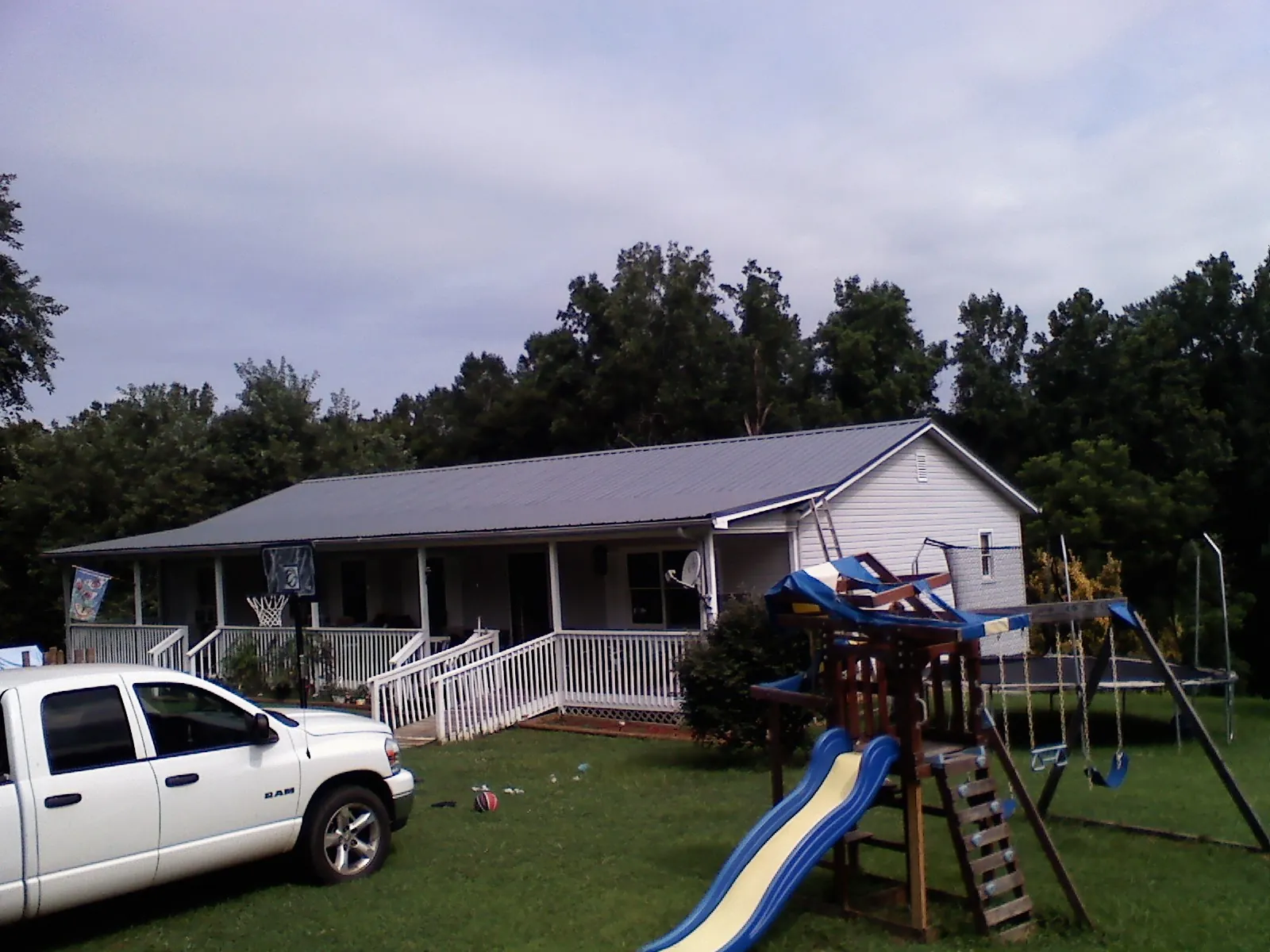 Dark metal roof on a country home with a full length front porch in Ashuelot