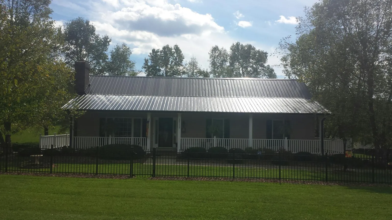 Gray metal roof on a brick ranch with a full width front porch — Gutter Guard Installation work by our crew in Ashuelot