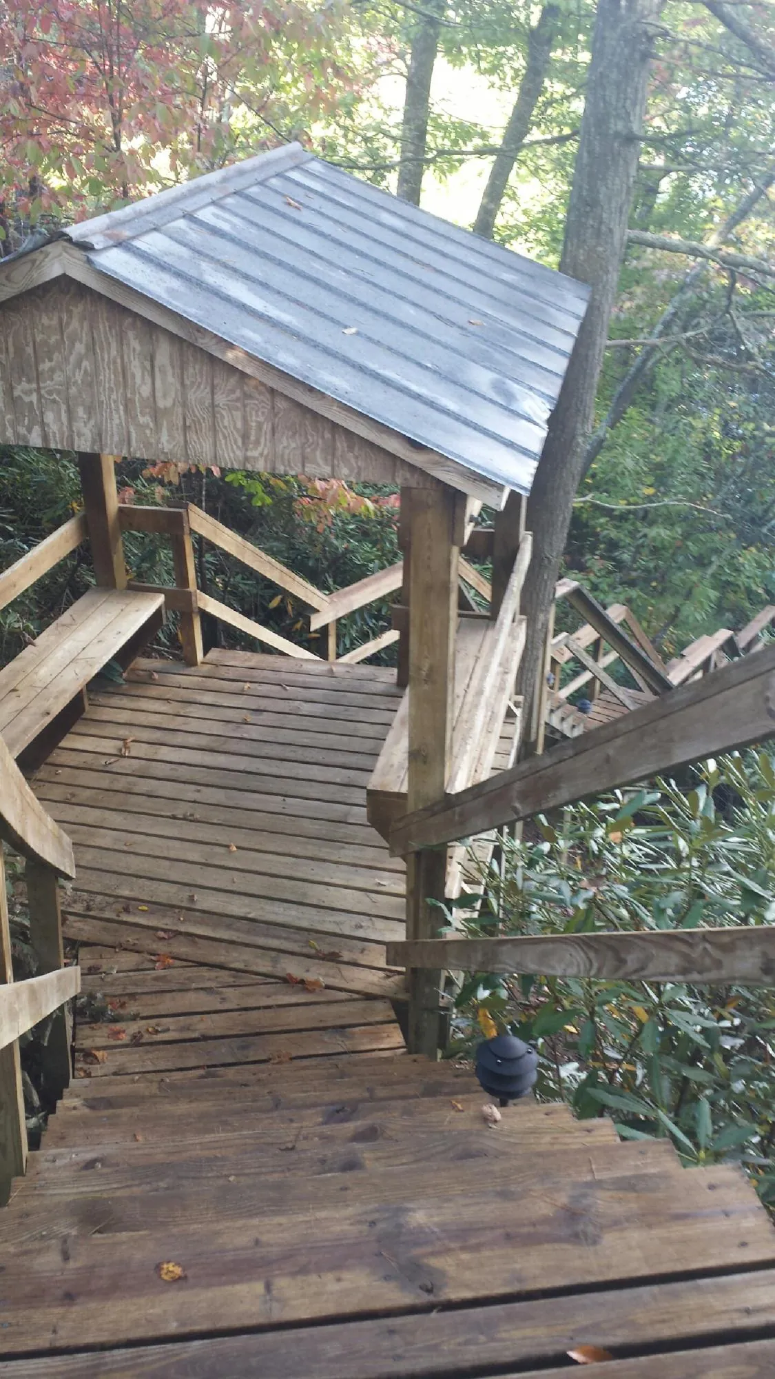 Metal roofed shelter over wooden steps on a wooded walkway — Skylight Repair & Installation work by our crew in Ashuelot