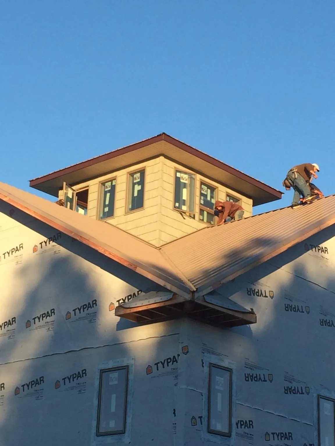 Roofers working around a rooftop cupola on a new metal roof at sunset — Roof Waterproofing in Ashuelot by Roofing Brothers